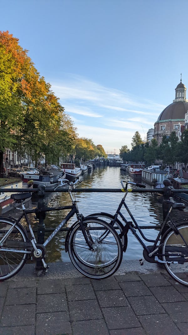 Sfeervolle stadsfotografie van het Singel in Amsterdam met geparkeerde fietsen op de brug en doorkijk naar de Ronde Lutherse Kerk.