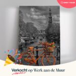 Oranje fiets versierd met bloemen op Amsterdamse brug.
