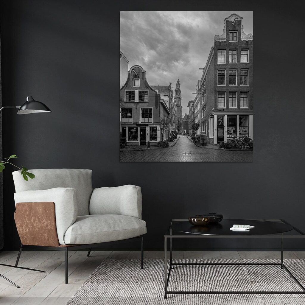 Artistieke zwart-wit foto van een doorkijkje vanuit de Jordaan richting de Westertoren met reflectie op natte klinkers.