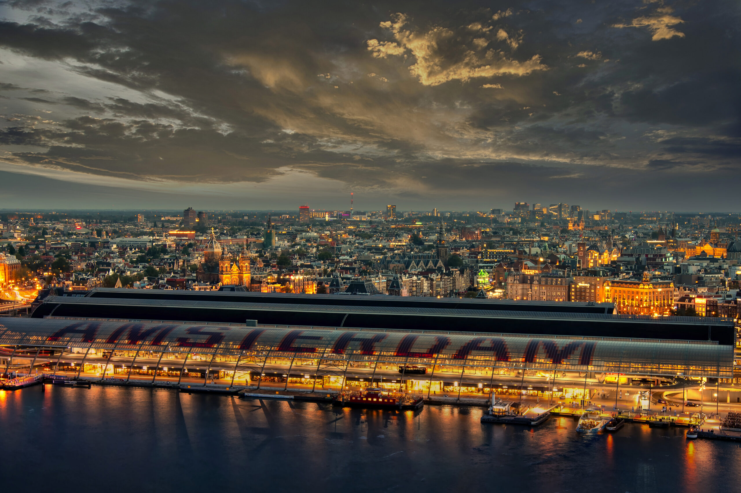 Skyline van Amsterdam tijdens het blauwe uur, gezien vanaf de A'DAM Toren met uitzicht over het Centraal Station en de historische binnenstad.