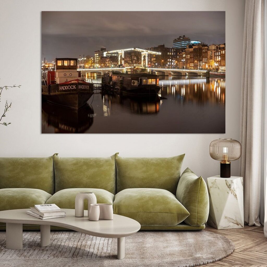 Grote canvas wanddecoratie van Amsterdam bij nacht als sfeervolle wandvulling boven een moderne bank.