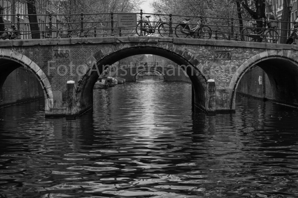 Reflections of historic bridges and canal houses on the Herengracht in Amsterdam.
