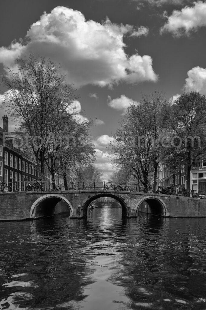 Symmetrical view of a bridge on the Herengracht with reflections in the canal water.