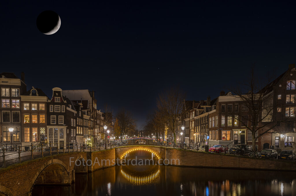 Illuminated bridge reflecting on the Keizersgracht during blue hour in Amsterdam
