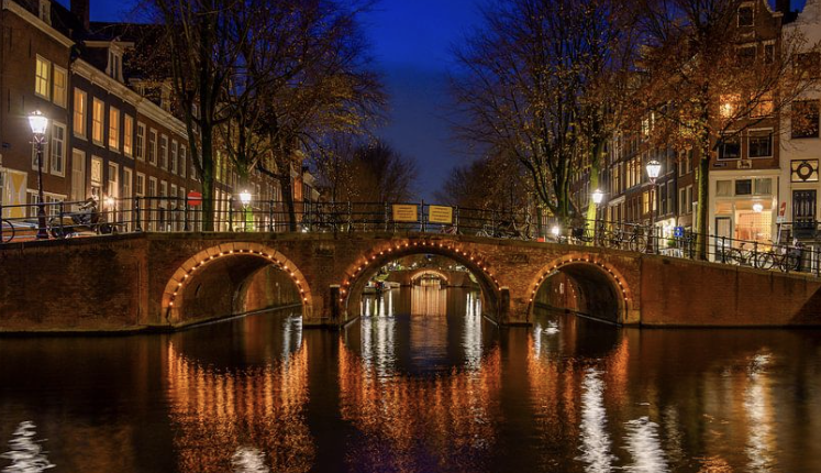 Blue hour at the Herengracht in Amsterdam with illuminated historic bridges and canal houses.