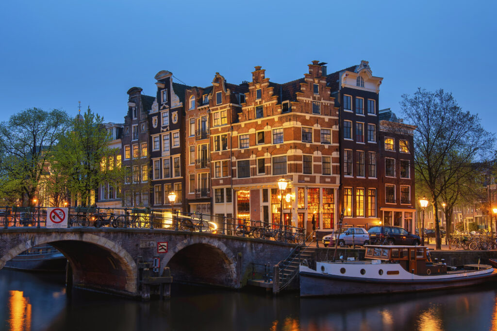 Verlichte Amsterdamse grachtenpanden aan het water tijdens het blauwe uur