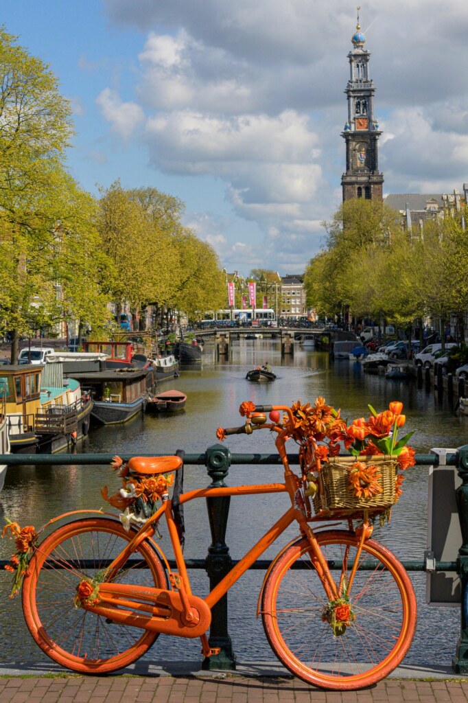 Oranje fiets aan een brugleuning met de Prinsengracht en Westertoren op de achtergrond