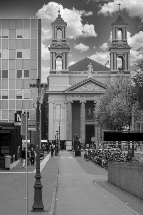 Zwart-witfoto van het Waterlooplein met de Mozes en Aäronkerk en wandelaars in Amsterdam